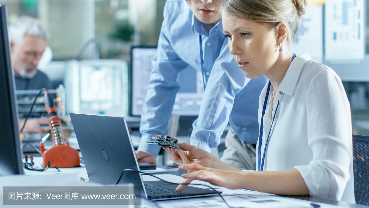 女計算機(jī)科學(xué)家將電路板連接到她的筆記本電腦并開始編程。她在先進(jìn)技術(shù)實(shí)驗(yàn)室工作。